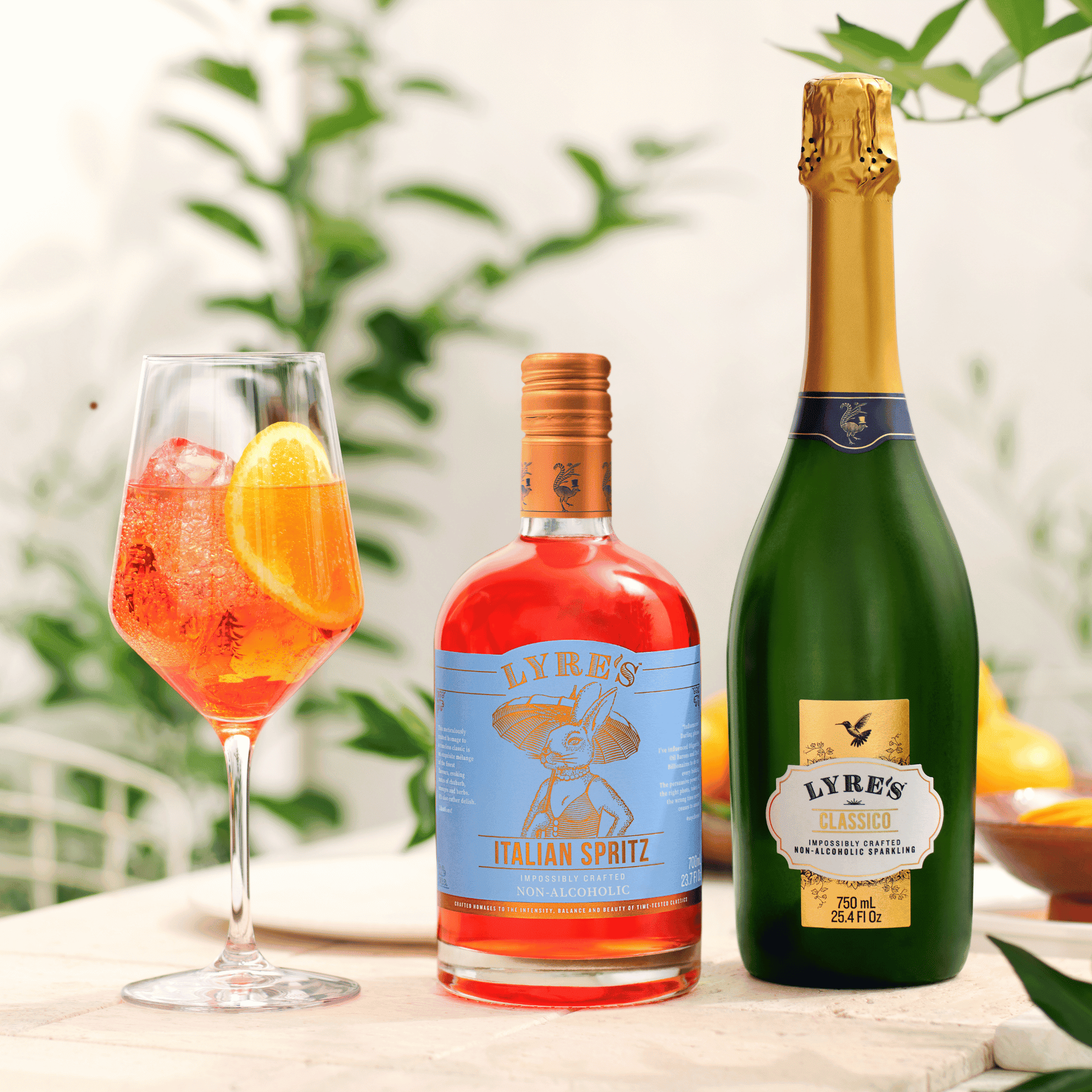 A bottle of Lyre's Italian Spritz and Classico with a glass of spritz on a table with a blurred greenery background.