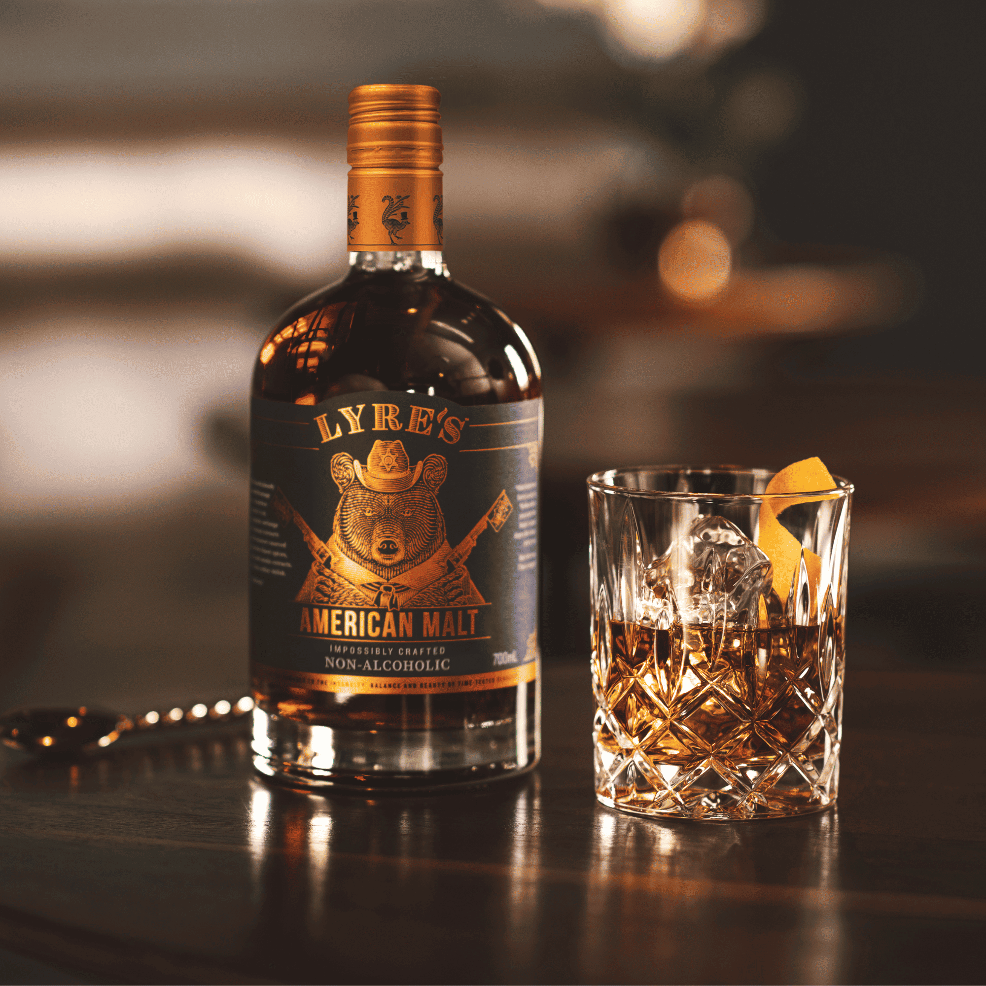 Bottle of Lyres American Malt non-alcoholic bourbon with an alcohol free Old Fashioned next to it.